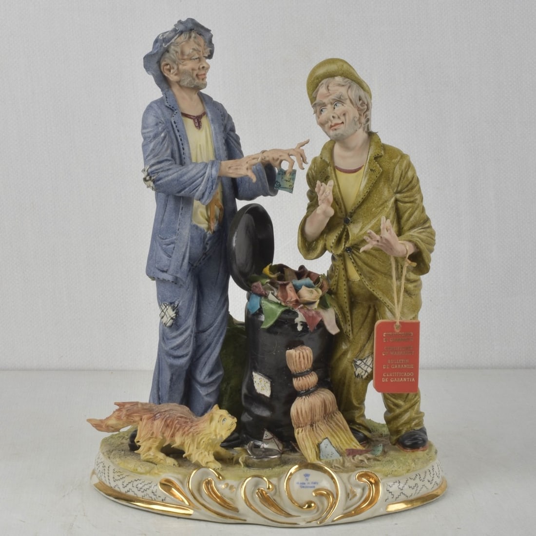 Italian Capodimonte Sculpture: Italian Capodimonte Sculpture. Depicting Two Hobos Rummaging in the Trash with a Cat to the Ground. Measures: 13-1/4" high, 9-1/2" wide, 6" deep. Kodner Galleries offers phone and absentee bidding at 