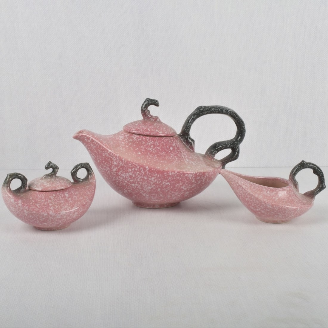 1950's Hull Aladdin Style Pottery: 1950's Hull USA Three (3) Piece Aladdin Style Pink Mottled Pottery Coffee/Tea Service. Each piece properly marked to the underside. Pot measures: 6-1/2" high, 10-3/4" wide, 6-3/4" deep. Kodner