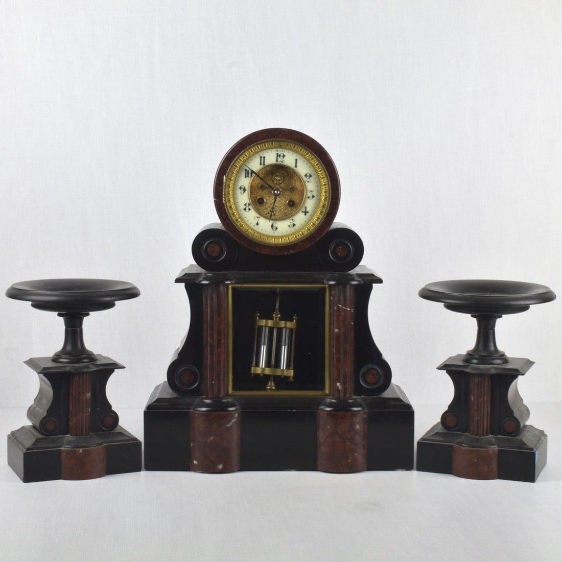 French Mantelpiece Garniture Clock: "Horlogerie De Paris" French Mantelpiece Garniture Clock and Side Pieces with Gold Highlights, Porcelain Dial, Brass Time & Strike Movement. 19th Century. Kodner Galleries offers phone and absentee