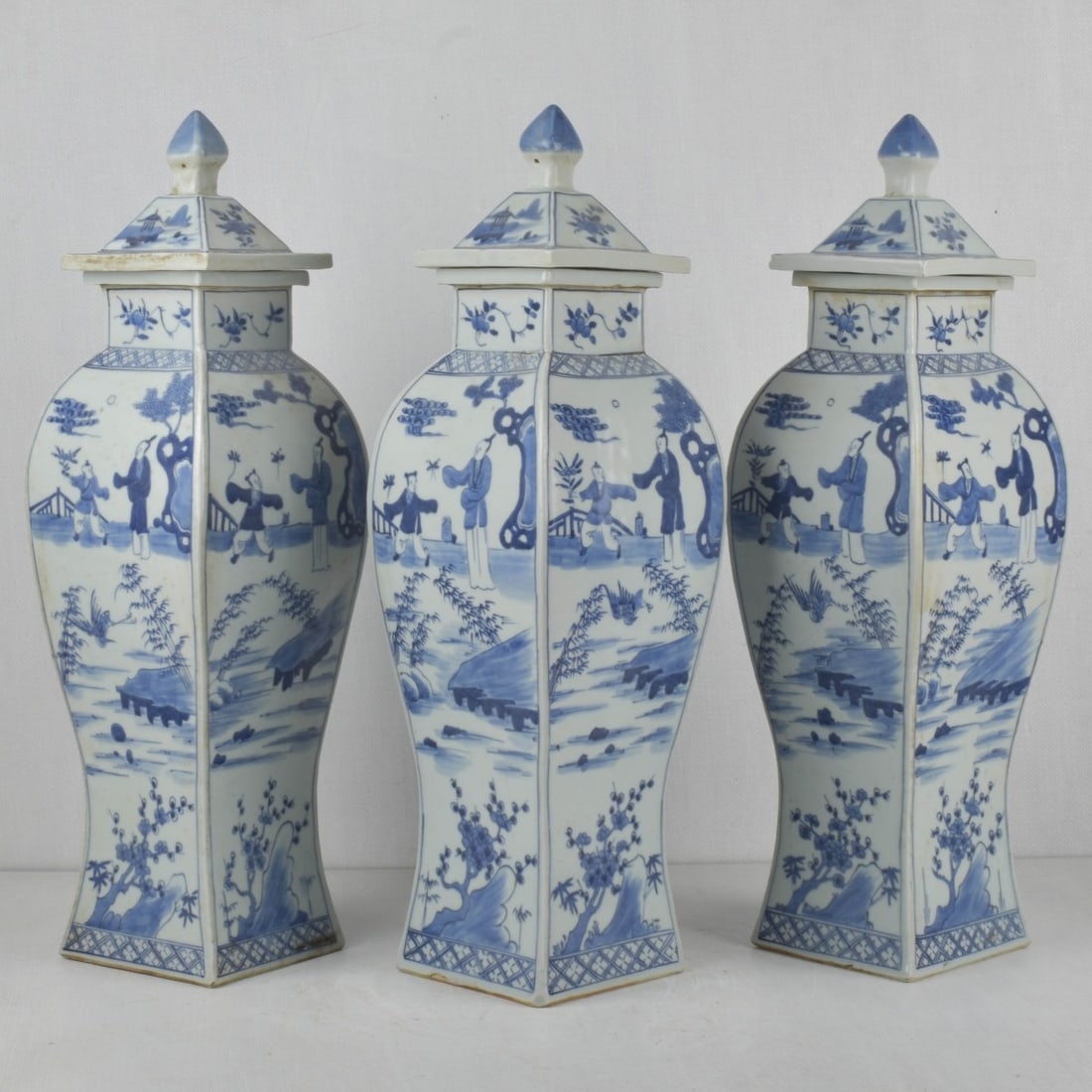 Antique Chinese Blue and White Vases: Three (3) Antique Chinese Blue and White Decorated Square Panel Vases in a Baluster Form. Painted panels of figures, birds and flowers, the square lids with knop finials. Measures: 22-1/2" tall, 6-1/2