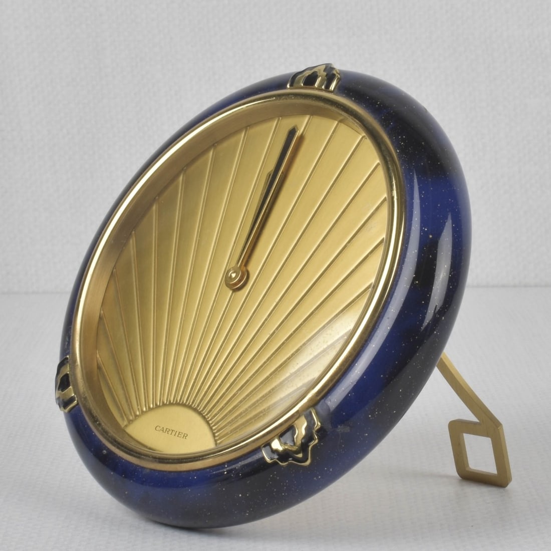 Cartier Desk Clock: Cartier Must de Cartier Gilt and Blue Art Deco Style Lacquer Desk Clock. Stamped "Cartier Quartz Swiss Made 62673". Measures: 5" diameter, 1-1/8" deep. Provenance: From an Important Coconut Grove,