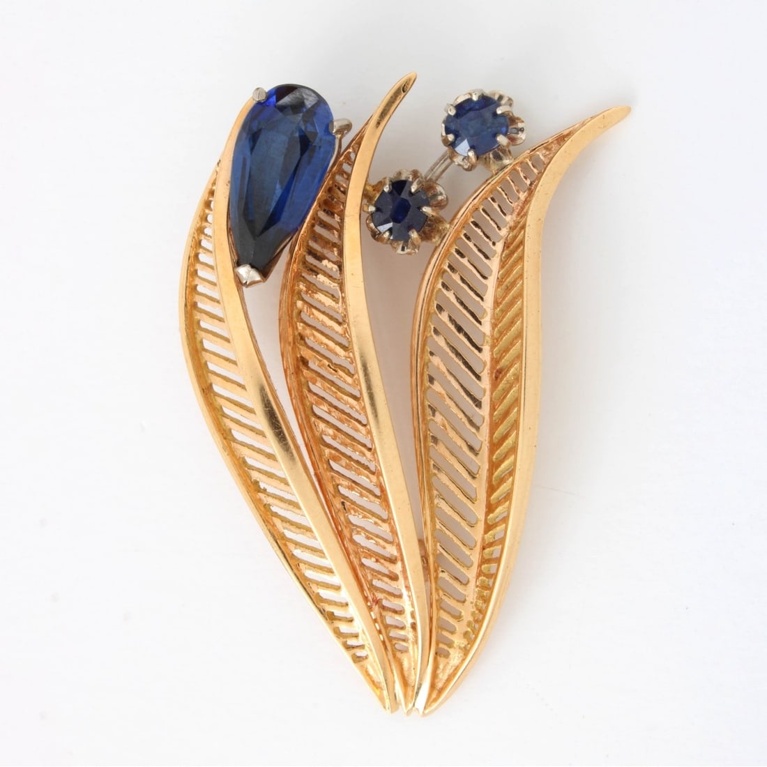Sapphire and 18K Brooch: Vintage Sapphire and 18 Karat Yellow Gold Leaf Brooch. Set with three (3) synthetic sapphires. Tested 18K. Measures 1-3/4" L. Approx. weight: 8.80 grams. Kodner Galleries offers phone and absentee