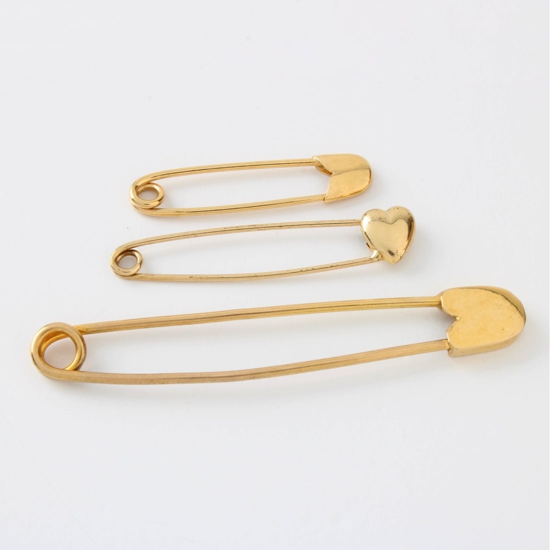 14K & 18K Safety Pins: Three (3) Vintage 14 Karat and 18 Karat Yellow Gold Safety Pins. The largest is 18K and measures 2-1/2" L. The two smaller are 14K, the largest of these measures 1-1/2" L. Approx. total weight: 5.2