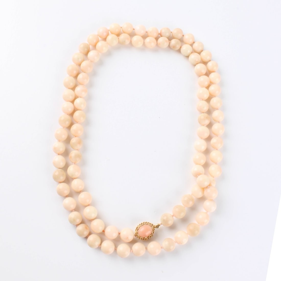 Coral and 14K Necklace: Vintage Single Strand 9mm Angel Skin Coral Bead Necklace with Coral and 14 Karat yellow Gold Clasp. Clasp stamped 14K. Necklace measures 34" L. Approx. weight 94.96 grams. Kodner Galleries offers phon