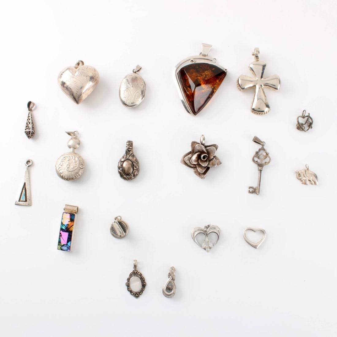 Sterling Pendants: Collection of Eighteen (18) Sterling Silver Pendants. Variously accented with amber, enamel and hardstone. Approx. total weight: 144.78 grams. Kodner Galleries offers phone and absentee bidding at a