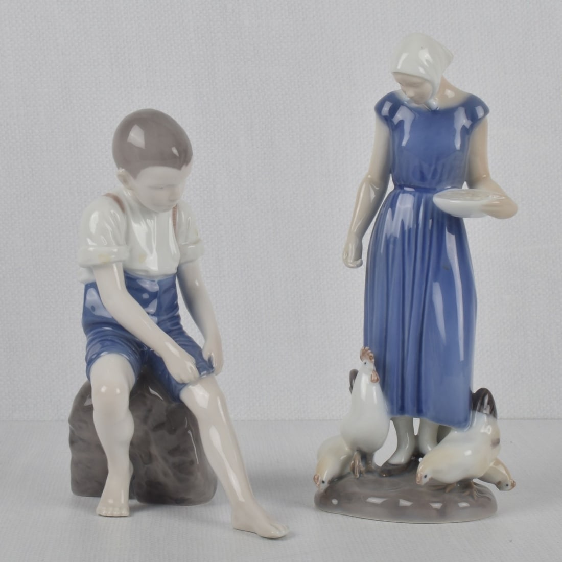B & G/Royal Copenhagen Porcelain Figures: Two (2) Bing & Grondah - Royal Copenhagen Porcelain Figures. Both properly marked to the undersides. One (1) "Boy on Rock" 1757 measures: 8" high, 6" wide, 3-1/8" deep, one (1) "Poultry Girl" 2220