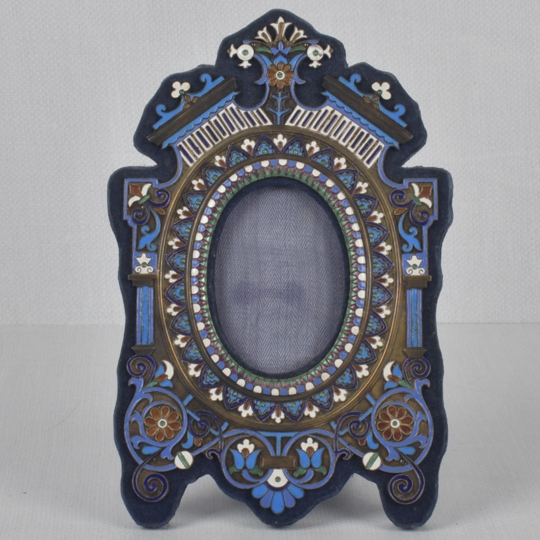 Champleve Cloisonne on Sterling: Champleve Cloisonne on Sterling Silver Picture Frame. In the style of Antip Kuzmichev. Stamped "STERLING" bottom right hand corner. Measures: 9-7/8" high, 6-1/2" wide, oval measures: 3-3/4" high, 2-1/