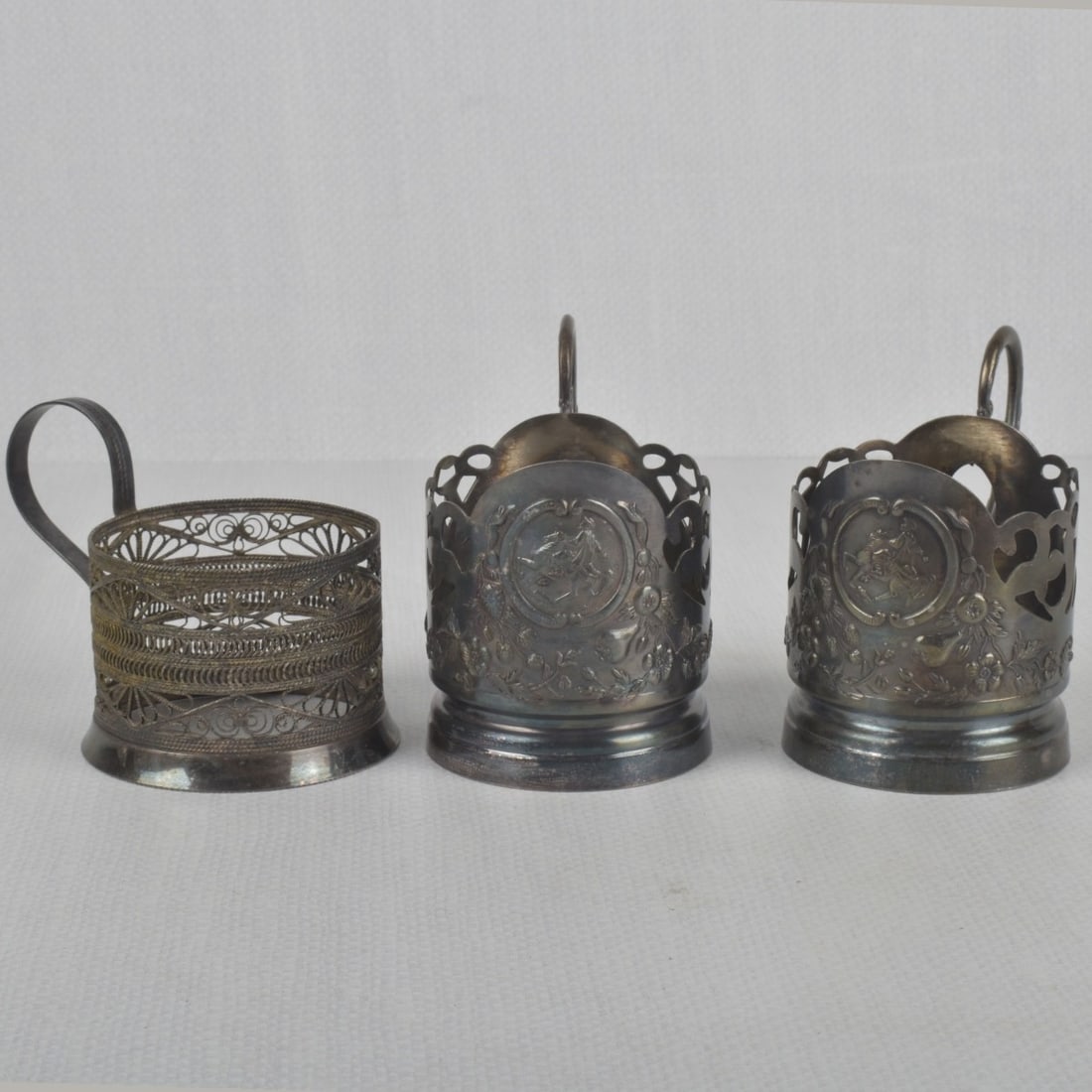 Russian 84 Silver Coffee/Tea Holders: Three (3) Russian 84 Silver Coffee/Tea Cup Holders of Different Makers and Different Patterns. Measures: 3-3/4" high, 2-1/2" diameter. Total gross weight: 9.06 troy ounces. Kodner Galleries offers