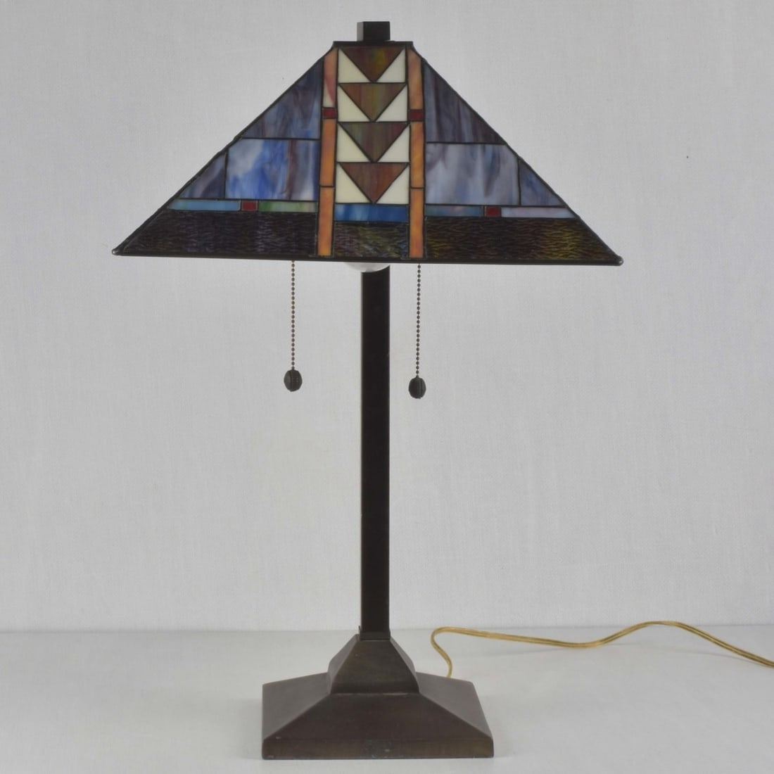 Tiffany-style Stained Glass Lamp: Tiffany-style Mission Stained Glass Two (2) Light Table Lamp with a Bronze Like Base with a Geometric Glass Shade. Shade measures: 8" high, 16" square, overall measures: 25-1/2" high. Kodner Galleries