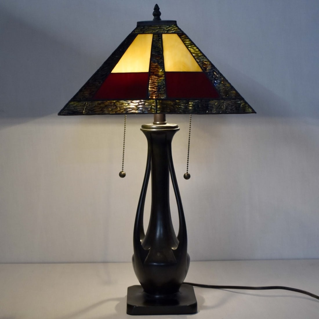 Tiffany-style Stained Glass Lamp: Tiffany-style Mission Stained Glass Two (2) Light Table Lamp with a Bronze Like Base with a Geometric Glass Shade. Shade measures: 8" high, 16" square, overall measures: 25-1/2" high. Kodner Galleries