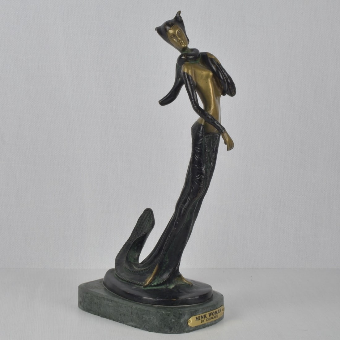 D.H. Chiparus Inspired "Mink Woman": D.H. Chiparus Inspired "Mink Woman" Bronze Sculpture on a Green Stone Base. Sculpture measures: 15-1/4" high, 7-1/2" wide, 3-3/4" deep, base measures: 1" high. Kodner Galleries offers phone and