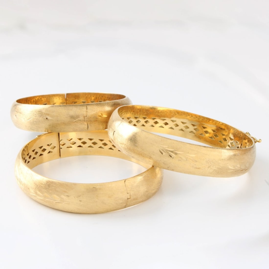 14K Bangle Bracelets: Three Vintage 14 Karat Yellow Gold Hinged Bangle Bracelets with Florentine Etched Design. Measure approx. 2-1/2" diameter. Approx. total weight: 45.50 grams. Kodner Galleries offers phone and