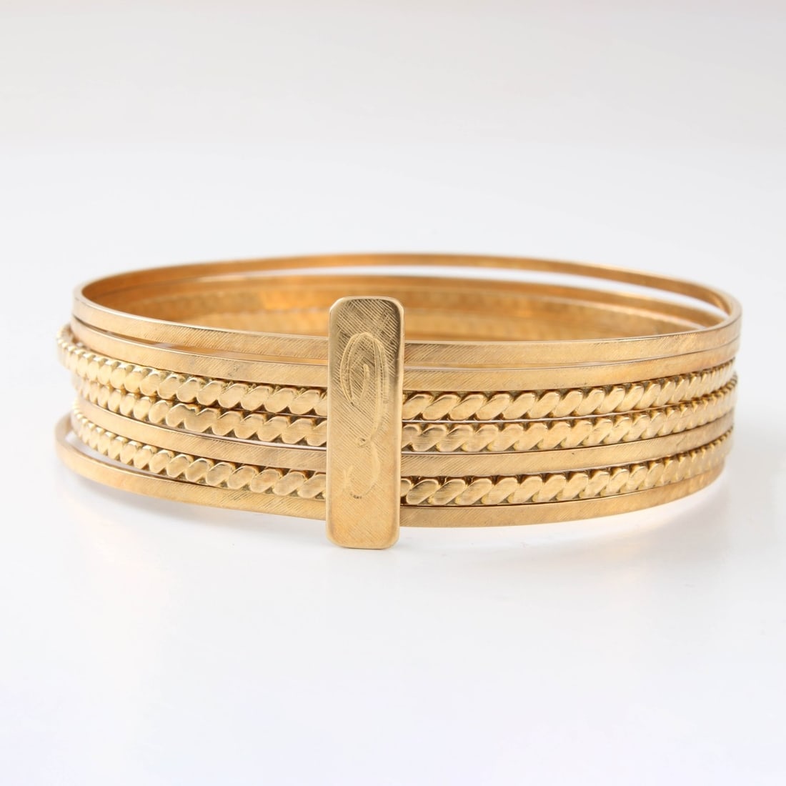 18K Stacked Bangle Bracelets: Vintage Set of Seven (7) Stacked Bangle Bracelets with Retro Design and with Yellow Gold Clasp. Measure 2-1/2" diam. Approx. total weight: 22.25 grams. Kodner Galleries offers phone and absentee