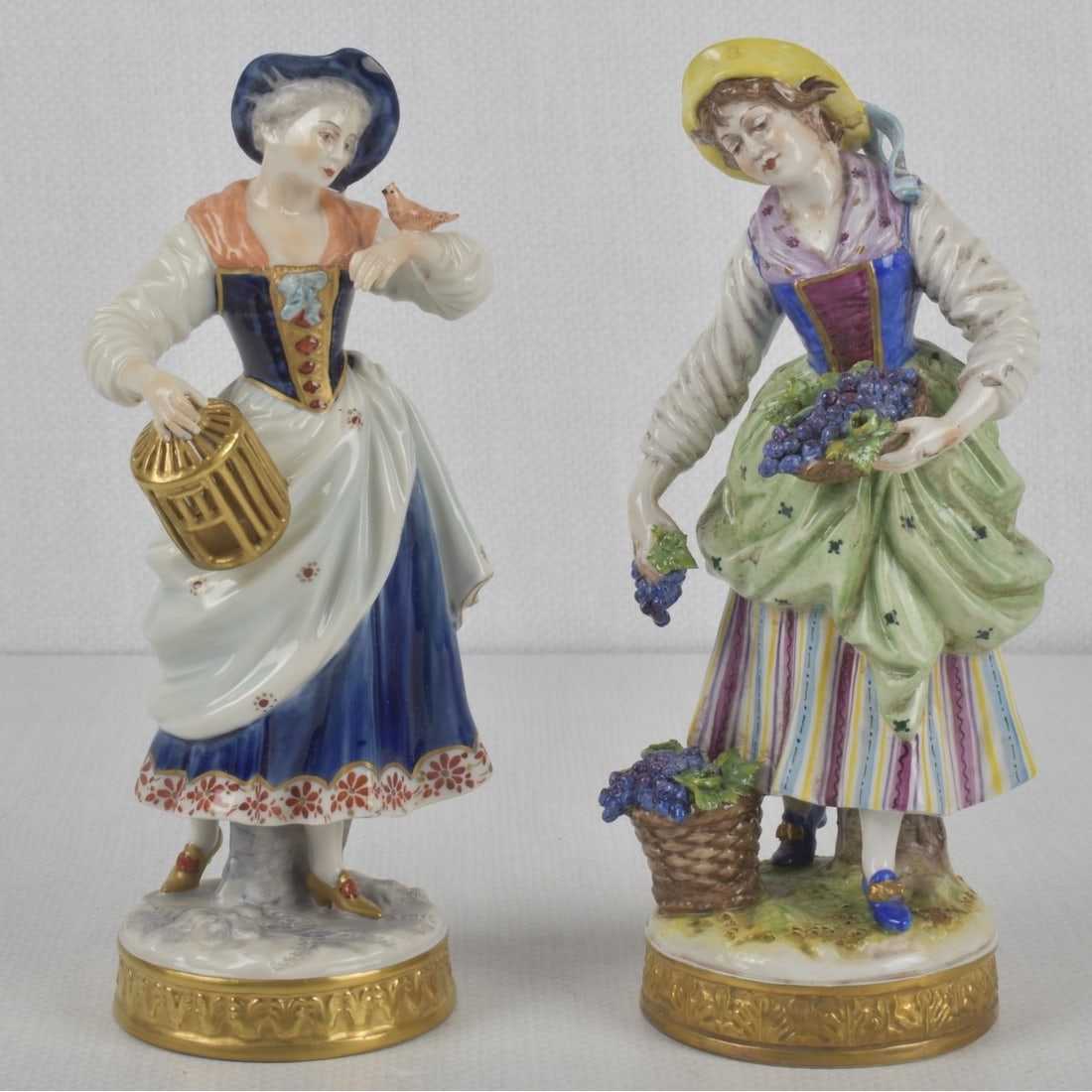 German Rudolstadt Volkstedt Figures: Two (2) German Rudolstadt Volkstedt Porcelain Figures. Properly marked to the undersides. Tallest measures: 8" high, 3-1/2" wide, 2-3/4" deep. Kodner Galleries offers phone and absentee bidding at a l
