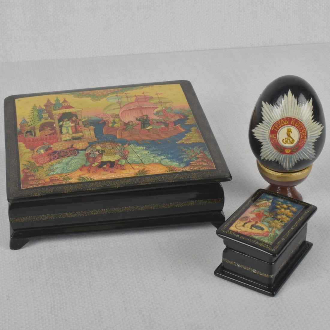 Russian Lacquer Papier Mache: Collection of Three (3) Russian Lacquer Papier Mache Pieces. Comprising two (2) boxes and one (1) egg. Largest box measures: 2" high, 6-1/2 square, smaller box measures: 1-1/2" high, 1-7/8" wide,