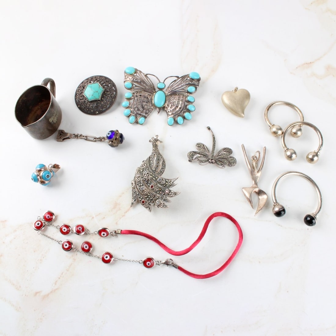 Lot of Sterling Silver Jewelry: Lot of Sterling Silver Jewelry. Consisting of brooches, a small cup, key rings, pendants, necklace bracelets some with marcasite, stones, faux gem stones. Total gross weight: 160.20 grams. Kodner