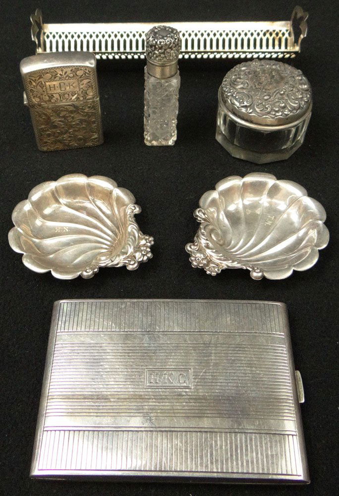 Seven (7) Sterling Silver Table Top Items. 1 Cigarette: Seven (7) Sterling Silver Table Top Items. 1 Cigarette Case Marked RB Co. Weighs 3.491 Troy Ounces. 1 Toast Rack Marked Webster. 1 Small Cut Glass Bottle. Marked (B). 2 Nut Dishes Marked Lunt. 1 Light