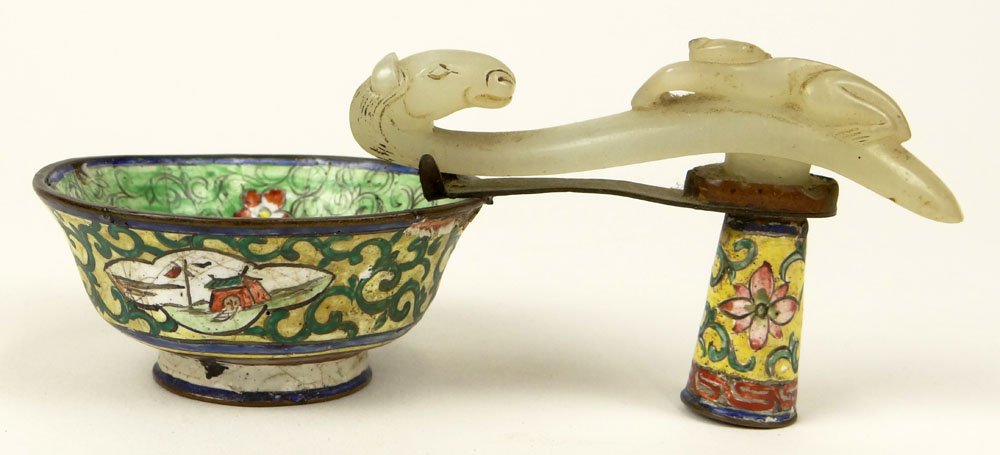 19th C Chinese Peking Enamel Cup with White Jade Belt: 19th C Chinese Peking Enamel Cup with White Jade Belt Buckle Handle. Enameled Scene in Center, the Jade Carved in Figural Relief. Unsigned. Damage to Emale "AS IS" Condition. Measures 2 Inches Tall, 5