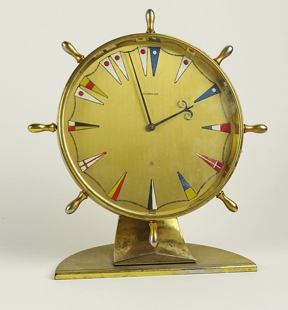 Vintage Guardier Brass Table Clock. Fun Ship wheel and: Vintage Guardier Brass Table Clock. Fun Ship wheel and Flag Motif. Signed Guardier, 8, Swiss, 15 Jewels. Wear and Rubbing, not in working Order. Measures 7 Inches Tall, 6-1/4 Inches Wide. Shipping $42