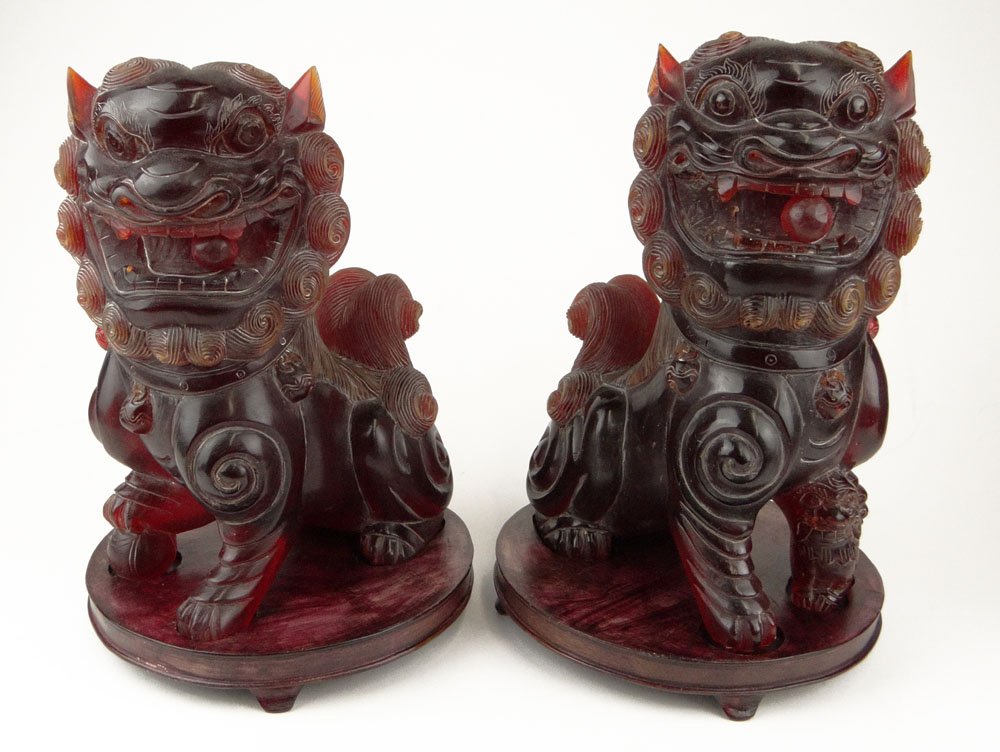 Pair of 20th Century Chinese Carved Cherry Amber: Pair of 20th Century Chinese Carved Cherry Amber Buddhist Lions on Wood Bases. Unsigned. Good Condition or Better. Measure 11-1/2 Inches Tall and 8 Inches Wide. Shipping $125.00