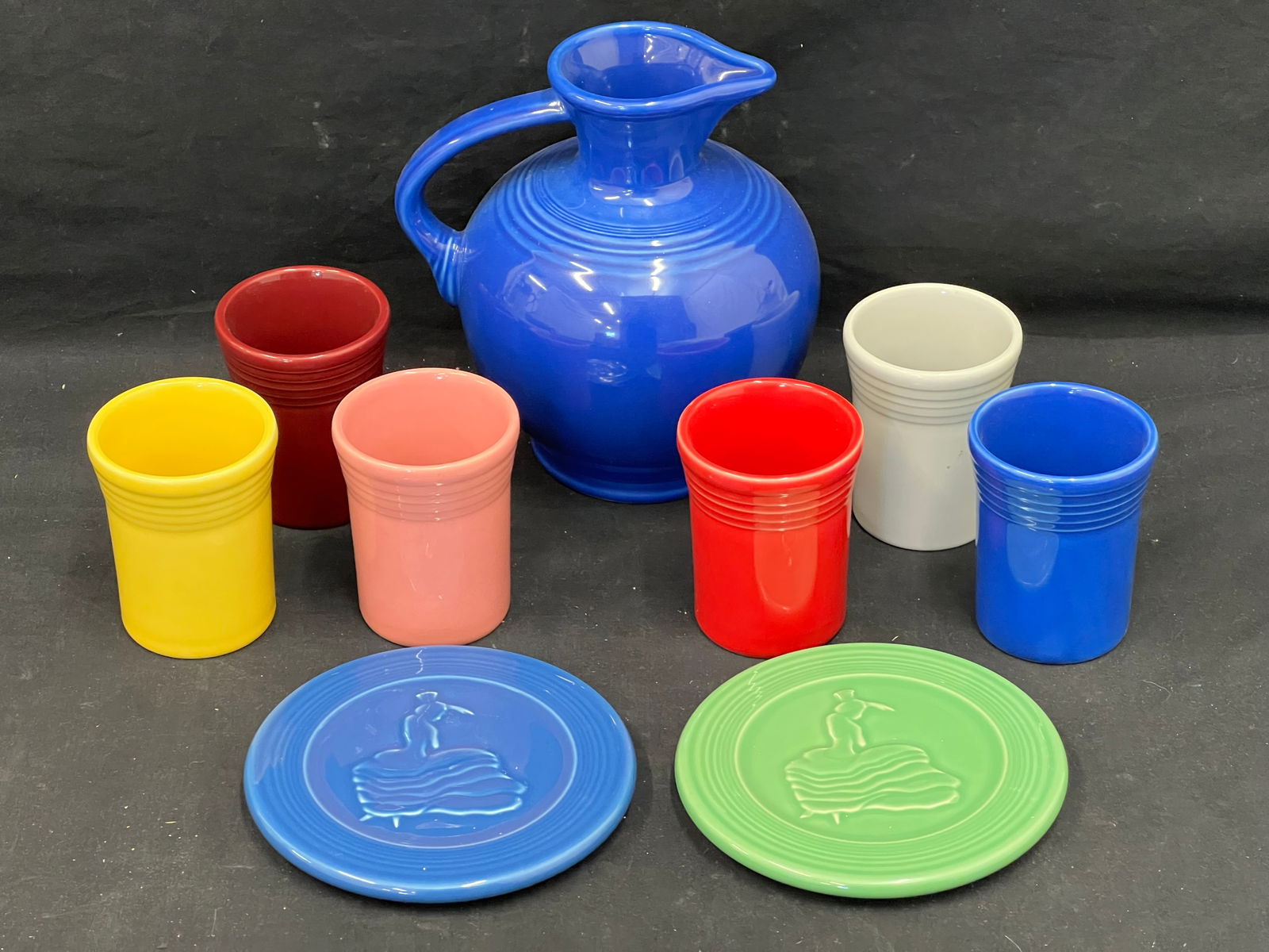 Fiesta HL Tumblers, Carafe & Trivets - (6)Asst Colored Tumblers 3.75''T, (2)Dancing Lady Trivets,: Fiesta HL Tumblers, Carafe & Trivets - (6)Asst Colored Tumblers 3.75''T, (2)Dancing Lady Trivets, (1)Carafe Pitcher
