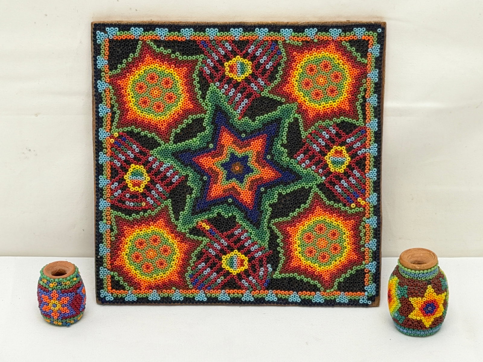 Huichol Folk Art Beaded Terra Cotta Beaded Vessels / Pots & Beaded Art on Wood Panel: (2)Miniature Terra Cotta Beaded Vessels / Pots 1"T to 1.5"T, (1)Beaded Artwork on Wood Panel with Center Star & Circular Motif to Represent the Peyote Flower 5.75" x 5.75"