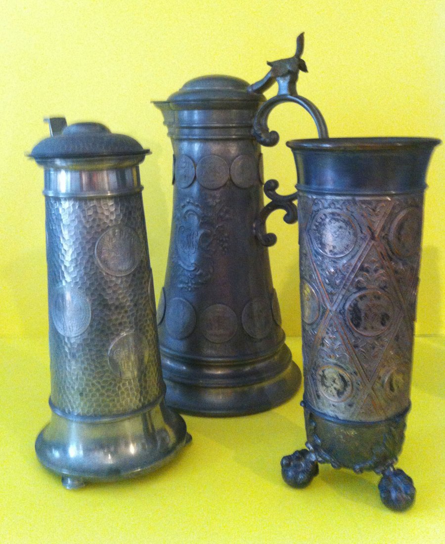 3 Antique Coin Tankered Stein And Cup: The larger one tankered measures 13 inches tall, the next coin stein measures 11 1/4 inches tall, and the smaller cup measures 11 inches tall.