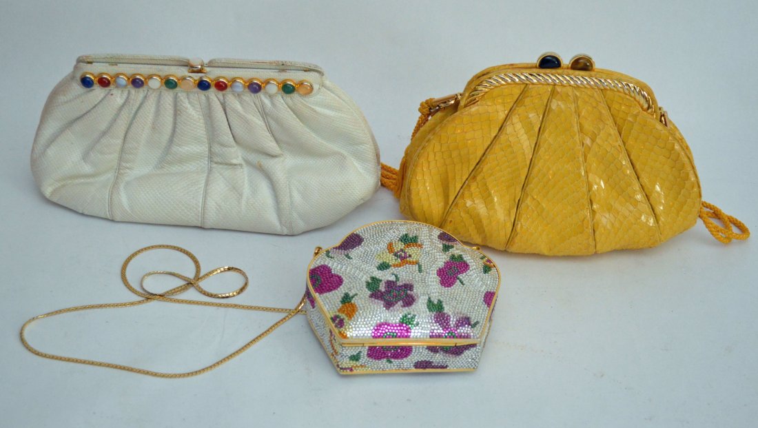3 Judith Lieber Bags Snakeskin, Lizard & Crystal: Hardshell Swarovski handbag with a gold change purse, measures 4.5" tall x 5.25" wide x 1 3/8" deep. Yellow python with onyx and tiger-eye stone bag 6.5" tall x 8.25" long. White lizard bag, missing s