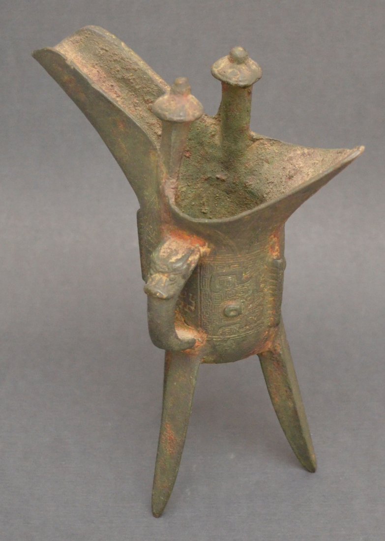 Chou Dynasty Chinese Bronze Libation Cup: Three legged bronze, Jou form libation cup from Chou dynasty, has molded relief. Measures 7.75" tall.
