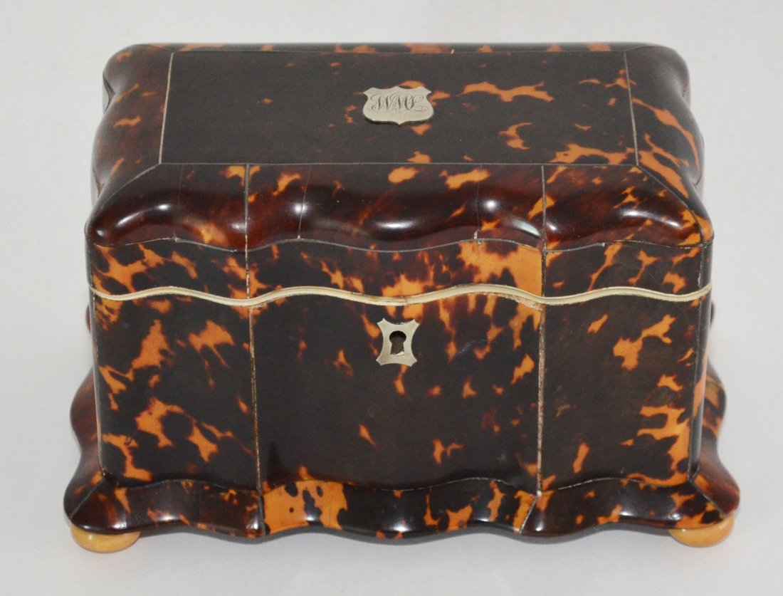 Antique Tortoise Shell & Sterling Tea Caddy: Early British antique tortoise shell tea caddy with silver escutcheon and monogrammed crest on lid. Measures 4.75" tall x 7.75" long x 5" deep at base.