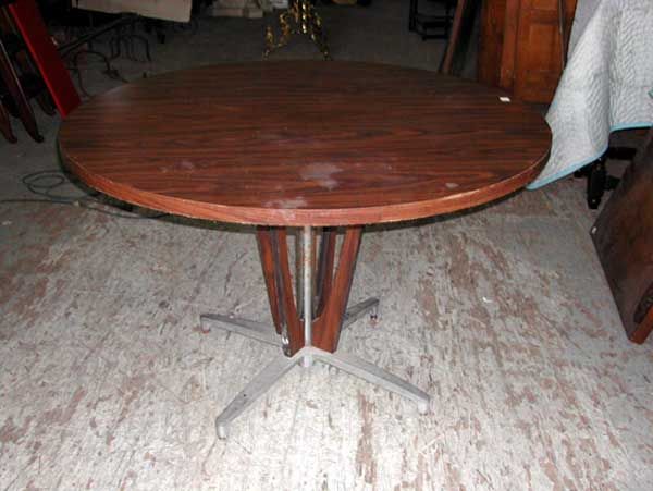 Art Moderne-Style Dining Table: Art Moderne-Style Dining Table, in the Art Deco taste, c. 1960-1970, the circular faux walnut formica top mounted to a cast aluminum and formica base, h. 30", w. 48".