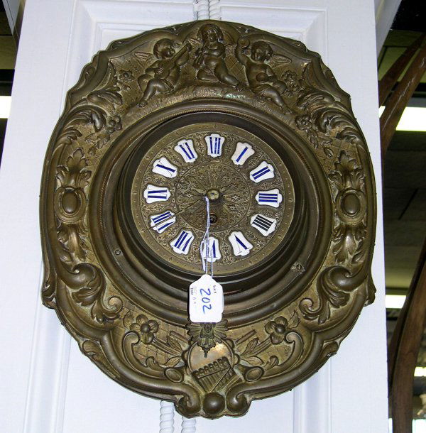 Napoleon III Embossed Brass Oval Wall Clock,: Napoleon III Embossed Brass Oval Wall Clock, in the Louis XV taste, third quarter 19th century, the cresting modeled as a trio of musical putti, the center of the basal edge with a musical trophée, t