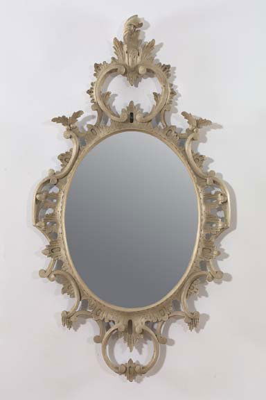 Pair of English Carved Wood Mirrors: Pair of English Carved and Antique-Gray-Painted Wood Oval Looking Glasses, in the rococo style of Thomas Johnson (1714-1778), the frames elaborately pierced and carved, the tall crestings modeled as p