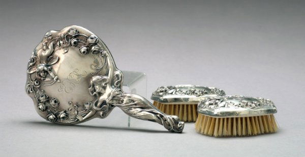 Sterling Silver Lady's Dressing Table Accessories: Three Sterling Silver Lady's Dressing Table Accessories, all ca. 1900, consisting of a Mermod and Jaccard Art Nouveau hand mirror in "Cupid" decor, w. 6", l. 10"; and a pair of American Art Nouveau "m