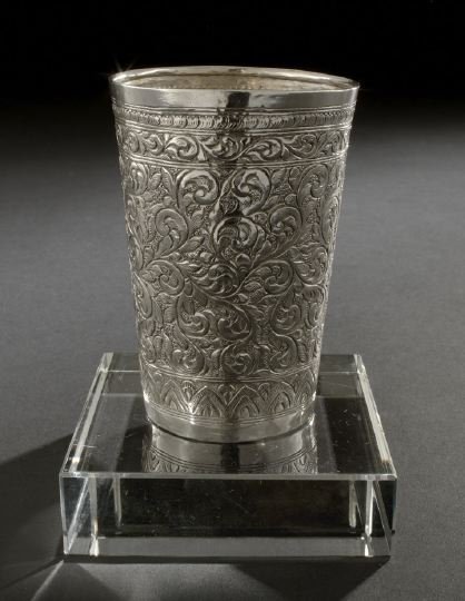 Asian Silver Beaker,: Asian Silver Beaker, first half 20th century, probably Tibet, of tapering cylindrical form, decorated all over with chased foliate scrolls on a pebbled ground, the bottom engraved with a snow lion, h.
