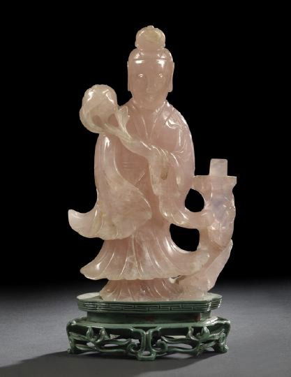 Large Chinese Rose Quartz Figure of Kwan Yin,: Large Chinese Rose Quartz Figure of Kwan Yin, first half 20th century, the goddess clad in flowing robes and holding a branch with peony blossom and standing next to a rocky outcrop with a book restin