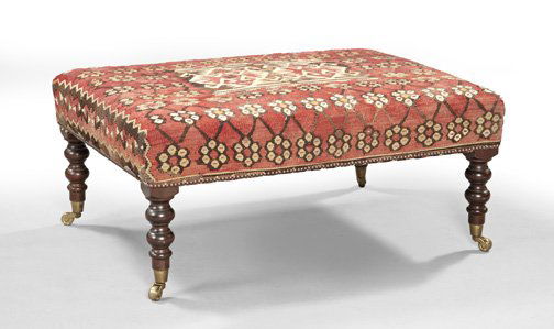 William IV-Style Mahogany Ottoman,: William IV-Style Mahogany Ottoman, the padded rectangular top upholstered in an antique kilim carpet, raised on bulbous turned legs ending in brass caps and casters, h. 17-1/4", w. 39", d. 28-1/2".