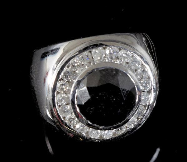 Gold and Black and White Diamond Ring: Gentleman's Fourteen-Karat White Gold and Black and White Diamond Ring, composed of a central bezel-set round brilliant-cut black diamond weighing 5.18 carats, surrounded by a channel set with round b