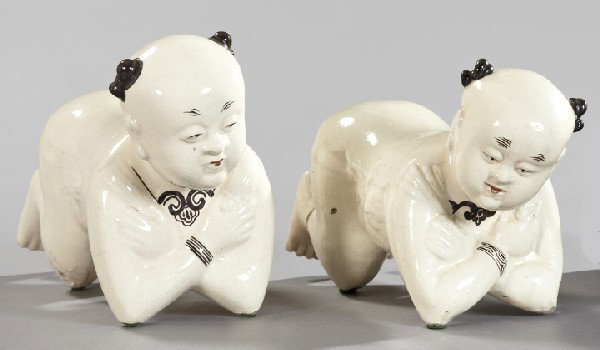 Chinese Provincial Glazed Pottery Pillows: Near Pair of Chinese Provincial Glazed Pottery Pillows, fourth quarter 19th century, modeled in the form of crawling infants and glazed in black-detailed ivory, h. 9-1/2", w. 6", l. 14".