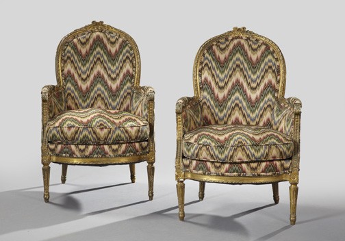 Pair of Louis XVI-Style Giltwood Bergeres,: Pair of Louis XVI-Style Giltwood Bergeres, fourth quarter 19th century, each with a domed crest centered by a floral carving, above a padded back, joined to the cushioned seat by like arms, over a gui