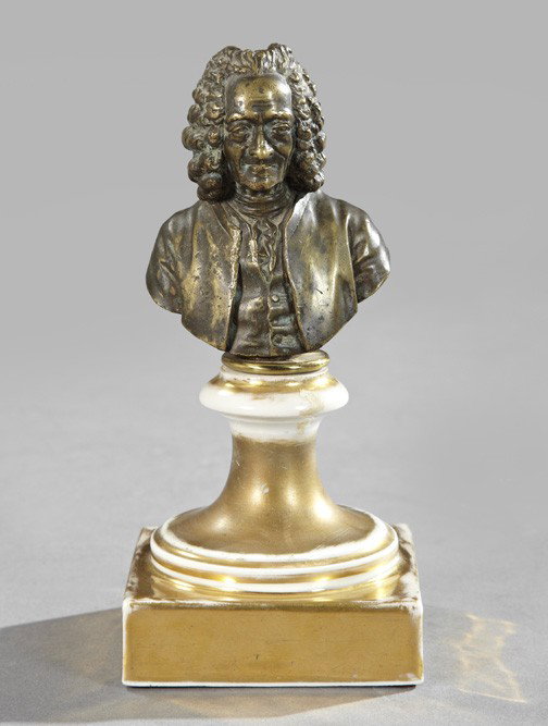 After Jean-Antoine Houdon (French, 1741-1828): After Jean-Antoine Houdon (French, 1741-1828), a patinated bronze bust of Voltaire, presented on a parcel-gilt porcelain socle base, h. 8", w. 3-3/4", d. 3-3/4".