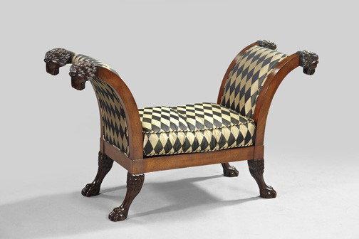 Regency-Style Mahogany Window Bench,: Regency-Style Mahogany Window Bench, by the Baker Furniture Company, the padded outscrolled arms terminating in lion-masque carvings, above a cushioned seat, raised on splayed legs terminating in carv