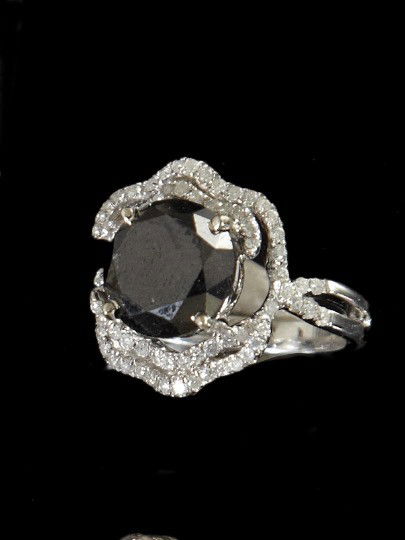 Gold and Black and White Diamond Lady's Ring: Interesting Fourteen-Karat White Gold and Black and White Diamond Lady's Ring, featuring a prong-set round brilliant-cut black diamond, weighing approximately 6.41 carats, set within a tiered round br
