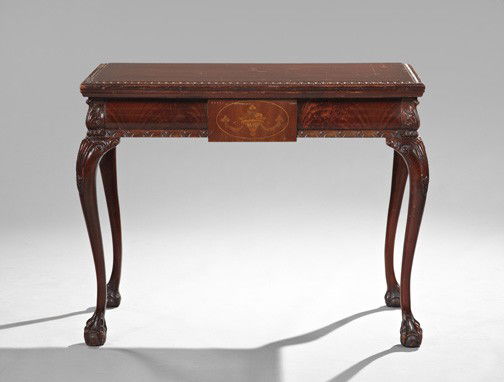 George III-Style Mahogany Games Table: George III-Style Mahogany Fold-Over Games Table, first quarter 20th century, the rectangular carved lift-top over a cushioned frieze centered by an urn-with-flowers inlay, raised on cabriole legs head