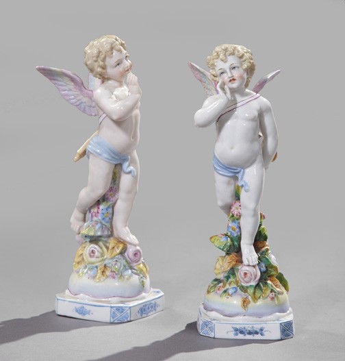 German Parcel-Gilt Porcelain Figures: Pair of German Hand-Painted and Parcel-Gilt Porcelain Figures, first quarter 20th century, in the Meissen taste, each in the form of a putto atop a floral-molded circular base, above a square blue and