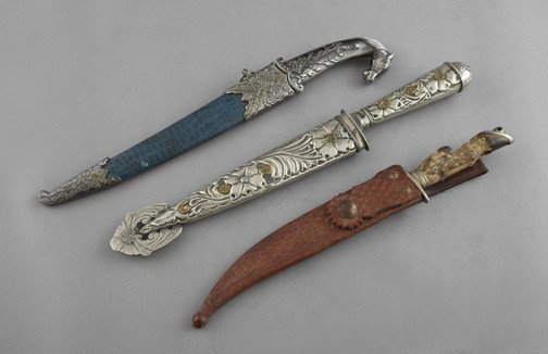Group of Three Ceremonial Knives and Sheaths,: Group of Three Ceremonial Knives and Sheaths, including an Argentinian example with embossed handle and scabbard, a Chinese example with horse-head handle, and a cloven-hoof example probably from a sm