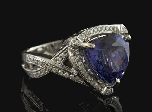 Gold, Tanzanite and Diamond Ring: Lady's Fourteen-Karat White Gold, Tanzanite and Diamond Ring, composed of a central prong-set 5.99-carat mixed triangular-cut natural Tanzanite set in a white gold mounting bead-set with sixty-seven r