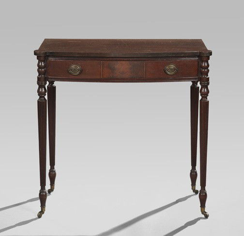Sheraton-Style Mahogany Side Table,: Sheraton-Style Mahogany Side Table, first quarter 20th century, the bowfront top with rounded projecting ends, above a conforming frieze fitted with a drawer, raised on reeded tapering circular legs e