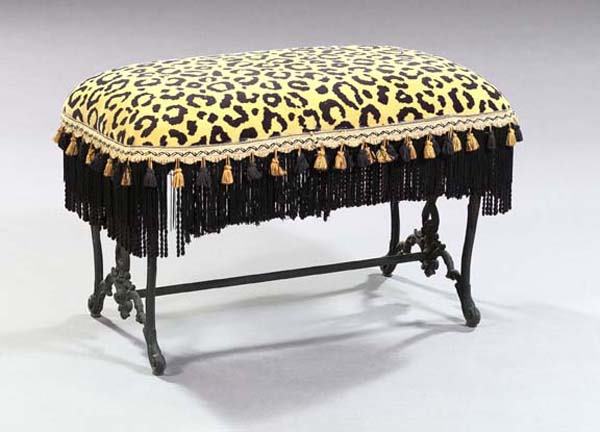 CAST IRON BENCH: Napoleon III-Style Upholstered Cast-Iron Bench, the oblong padded seat covered in a lion's print velvet with a black and gold tassellated trim, raised on foliated scroll cabriole legs, h. 20", w. 34",