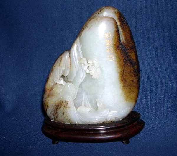 CH'IEN LUNG JADE DESK BOULDER: Attractive Ch'ien Lung Carved "Mutton Fat" Jade Scholar's Desk Boulder, featuring a figure in a boat on a rushing mountain river, fourth quarter 18th century, presented on a conforming elliptical Chin